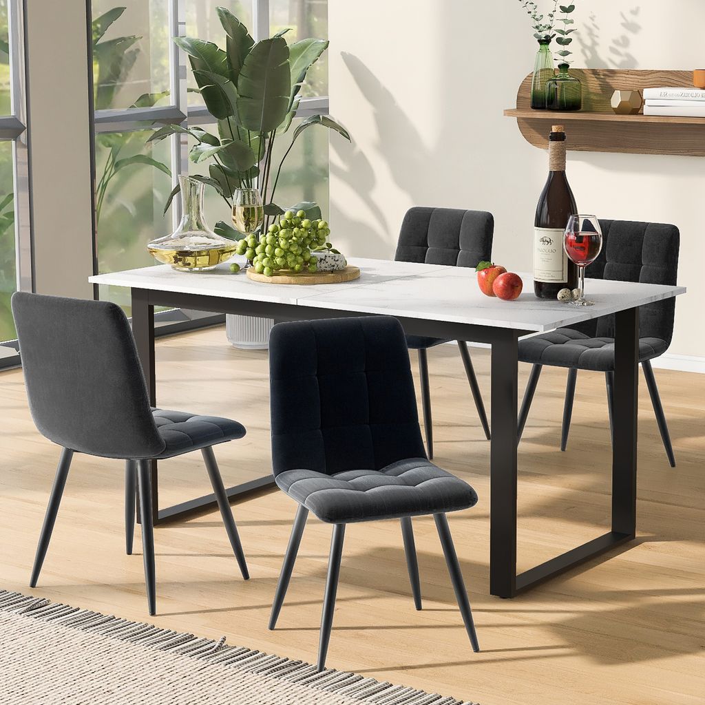 A dining table set with four chairs, a bottle of wine, and fruit on a marble-top table in a dining room.