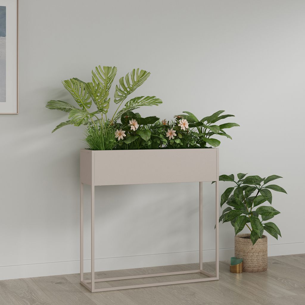 A planter with plants on a stand next to another potted plant, against a light gray wall.