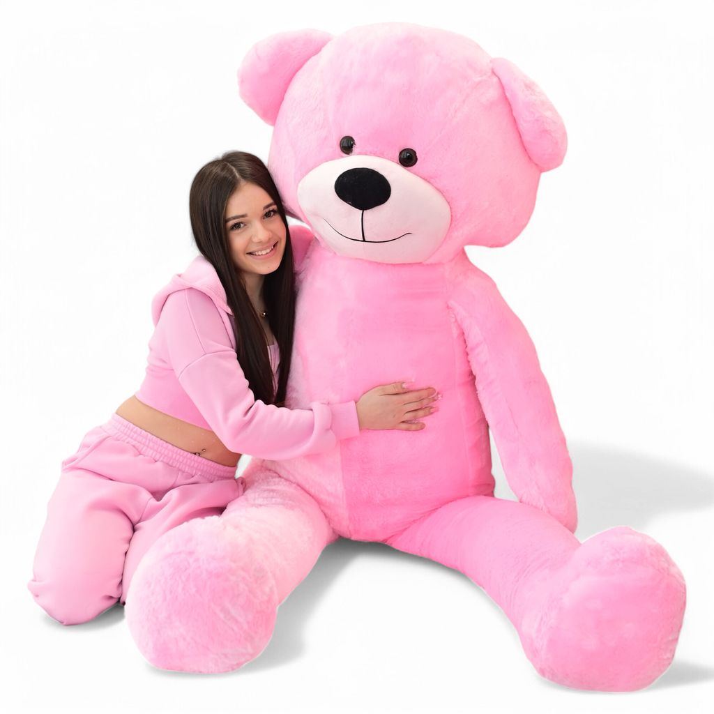 A young woman is hugging a giant pink teddy bear.