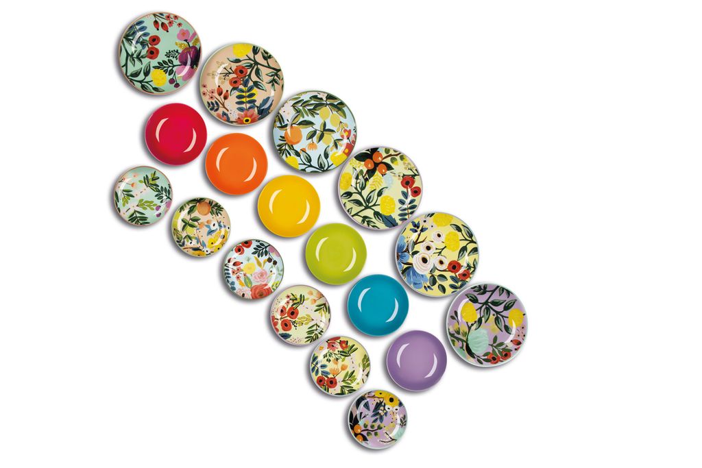 A collection of round plates with floral and fruit patterns, arranged diagonally on a white background.