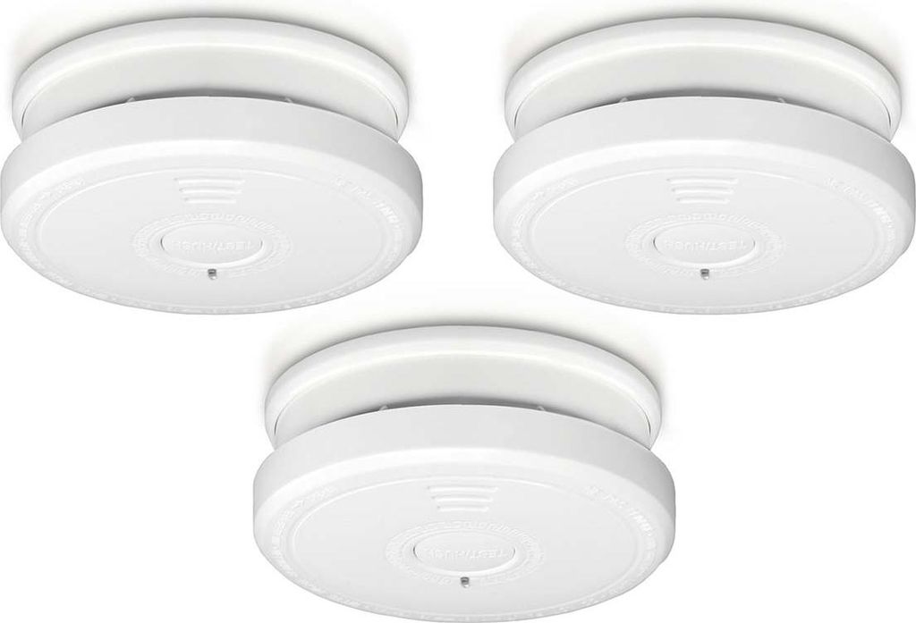 Three white smoke detectors mounted on a white ceiling.