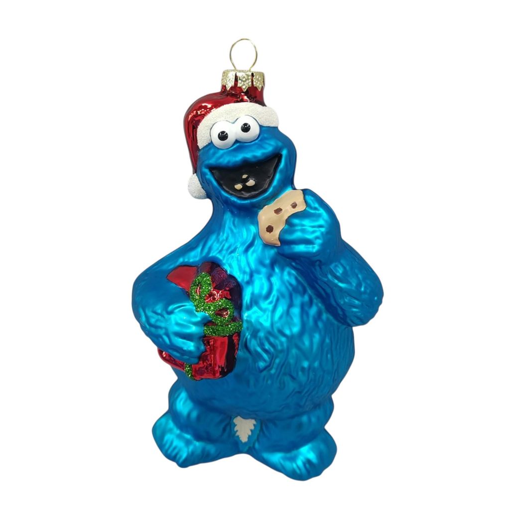 A Christmas ornament of the Sesame Street character Cookie Monster wearing a Santa hat and holding a present and a cookie.