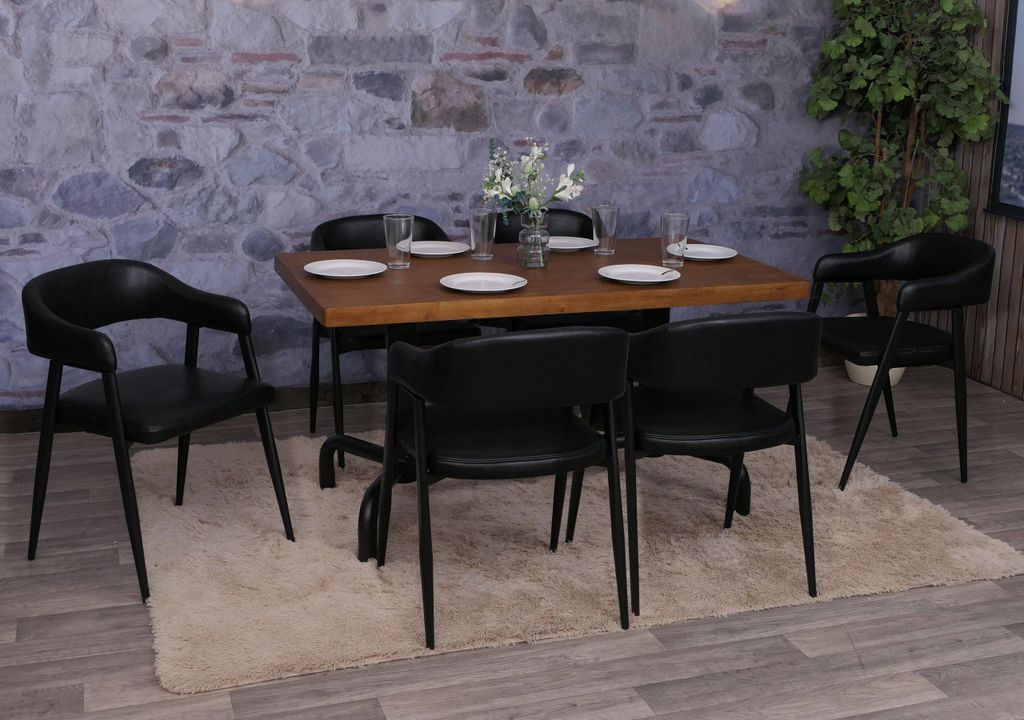 A dining set with chairs around a wooden table, placed on a rug in front of a stone wall.