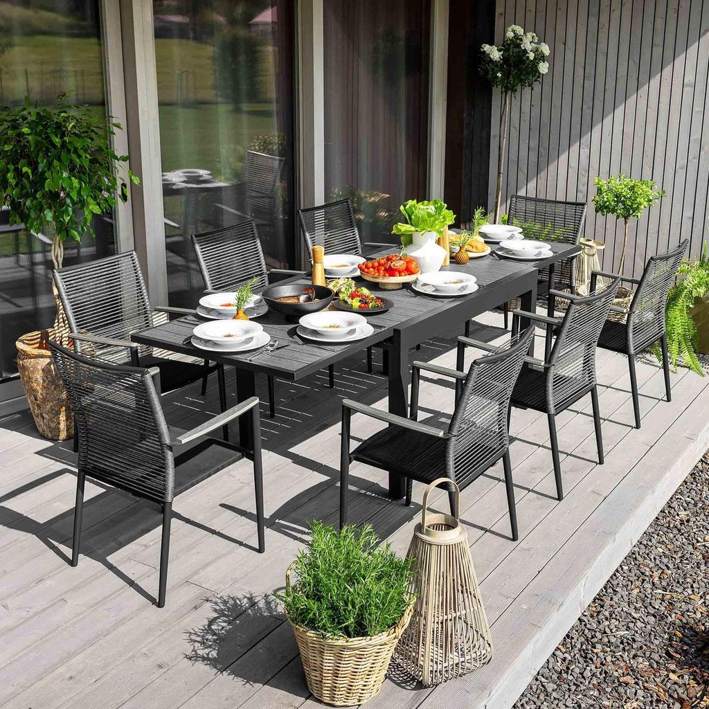 An outdoor dining set on a wooden deck, with food and drinks on the table.