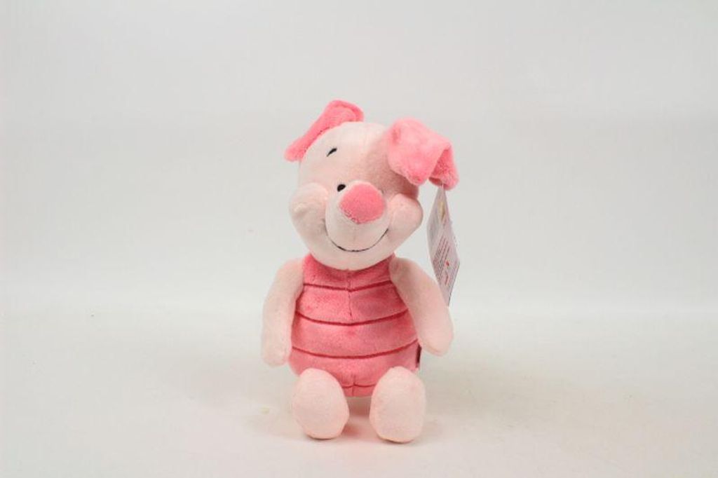 A pink plush toy piglet is sitting on a white background.