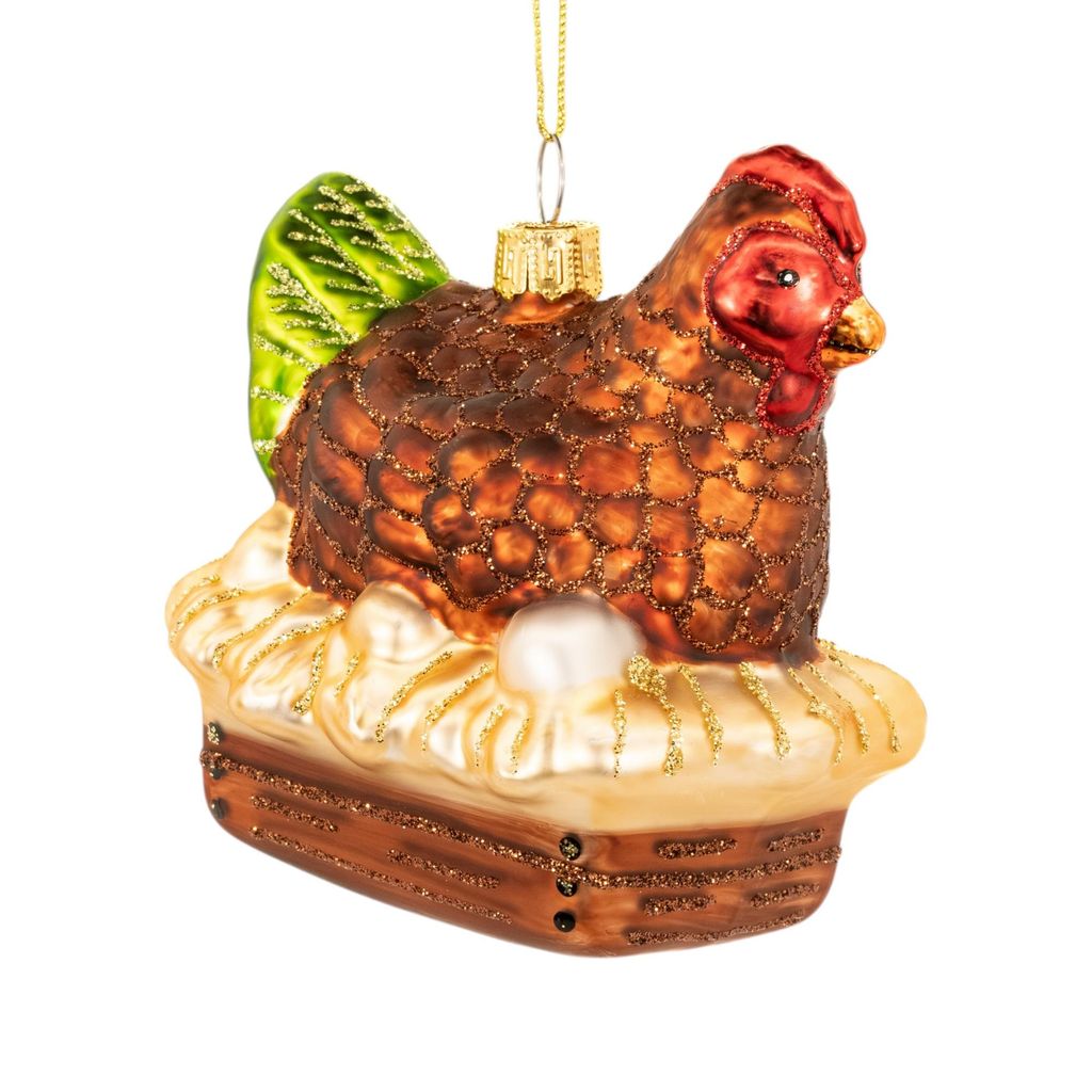 A glass Christmas ornament of a hen sitting on a nest with an egg.