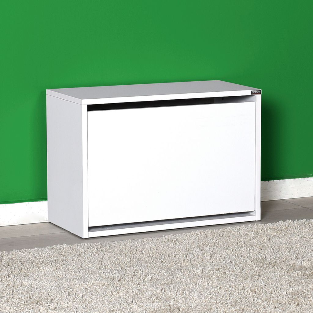 A white shoe cabinet against a green wall and a textured rug.
