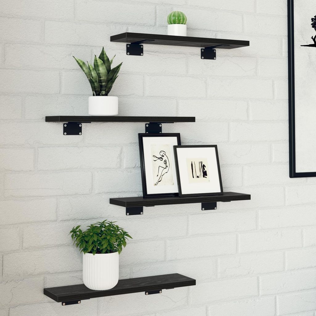 Four black wooden shelves are mounted on a white brick wall, each displaying decorative items.