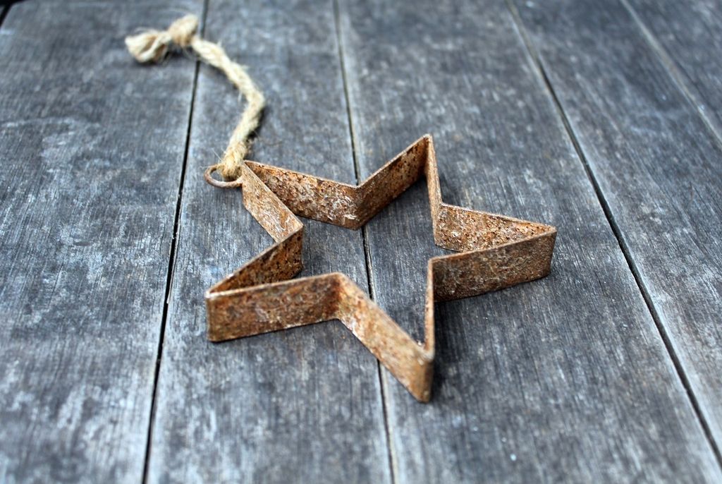 A rusty star-shaped cookie cutter is placed on a weathered wooden surface.