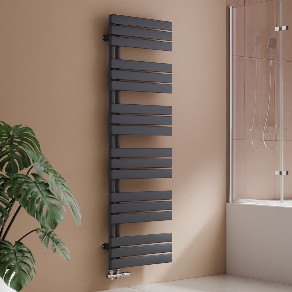 A modern anthracite radiator in a bathroom setting, next to a plant and a shower enclosure.