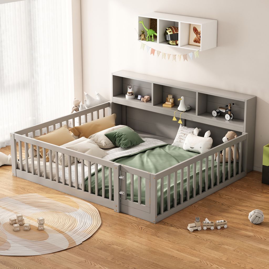A child's bed with a grey wooden frame and storage shelves, decorated with toys and bedding, in a room with wooden floors and a large window with sheer curtains.