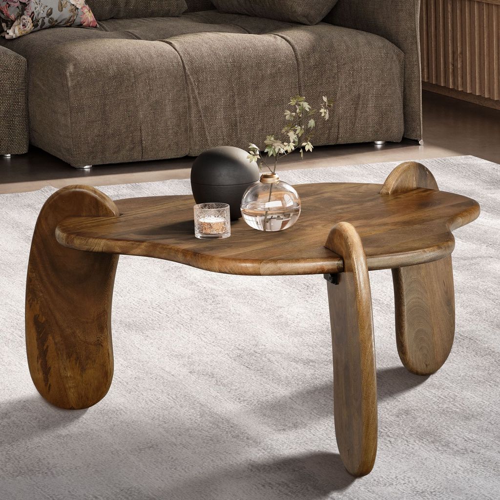 A wooden coffee table with decorative items on it, placed in a living room setting with a sofa in the background.