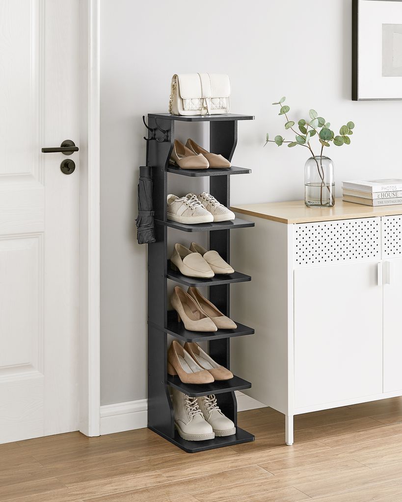 A black shoe rack with shoes and a handbag on display, placed next to a white cabinet and a door.