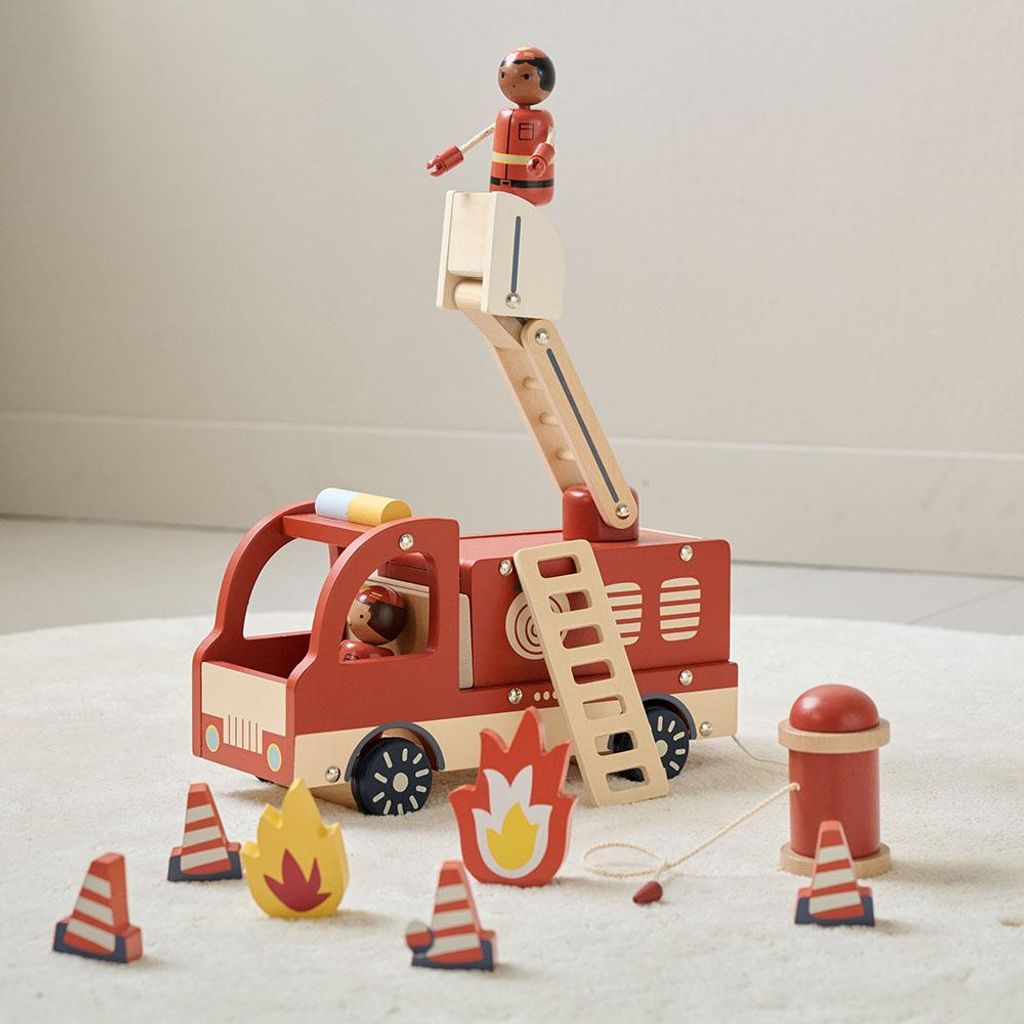 A wooden toy fire truck with accessories on a light-colored rug.