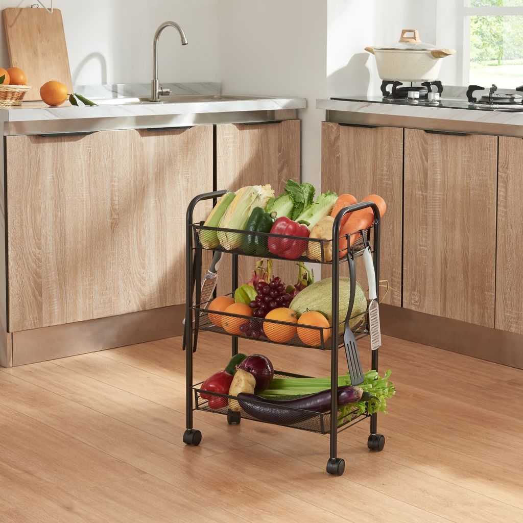 A kitchen scene with a three-tiered rolling cart filled with fruits and vegetables.