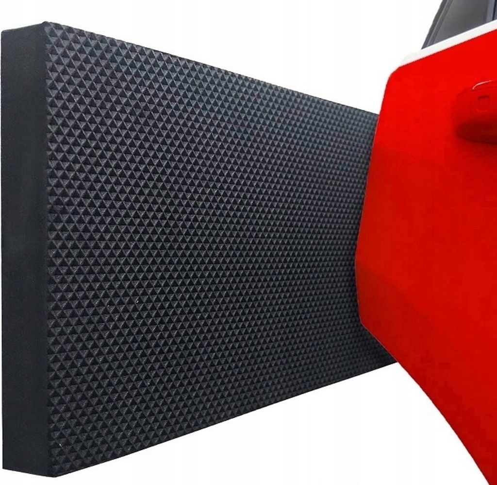 A black textured mat is placed next to a red car door.