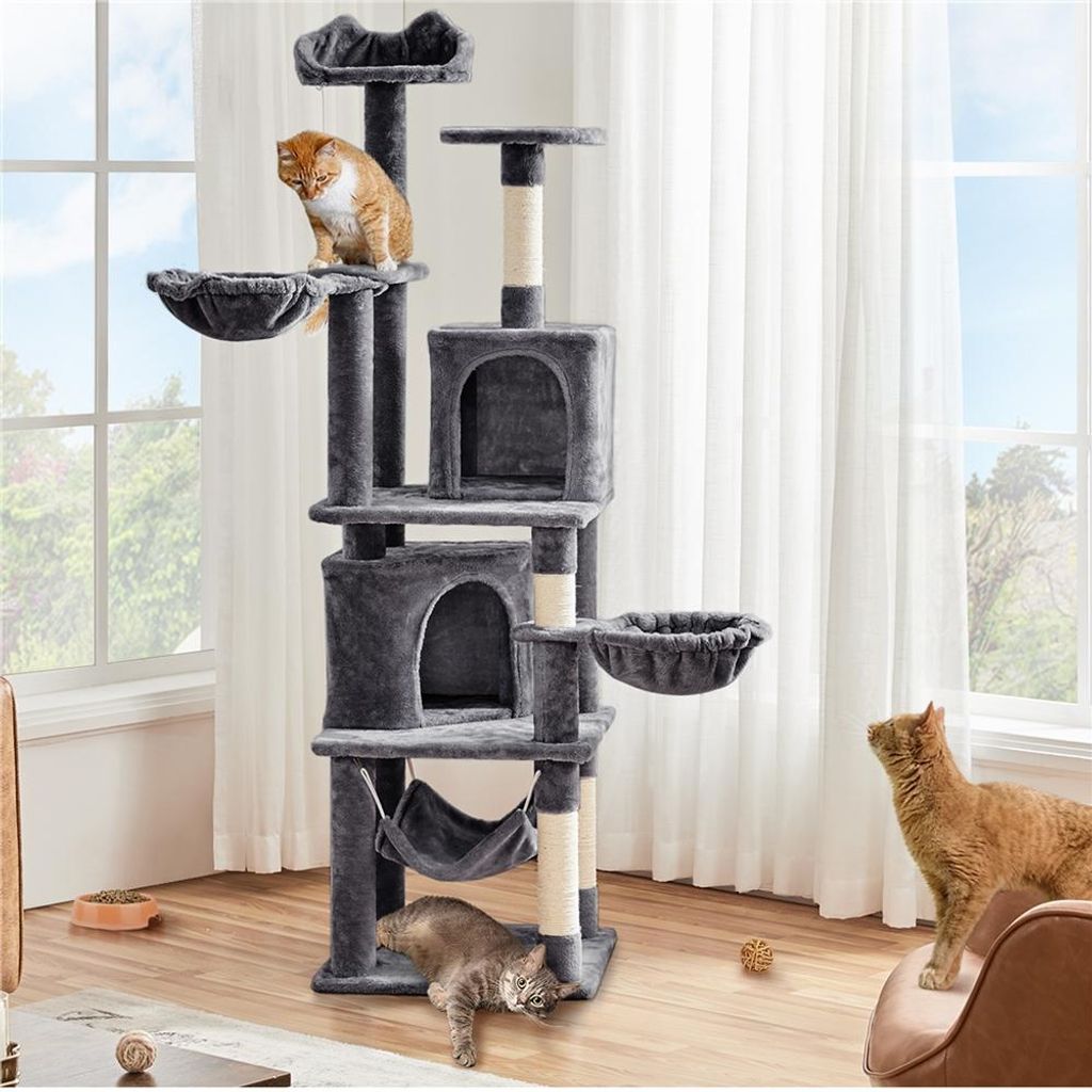 A multi-level cat tree with two cats interacting with it, placed in a room with natural light coming through a window.
