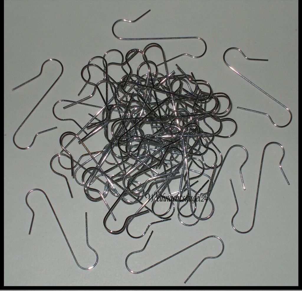 A pile of silver metal ornament hooks on a light gray background.
