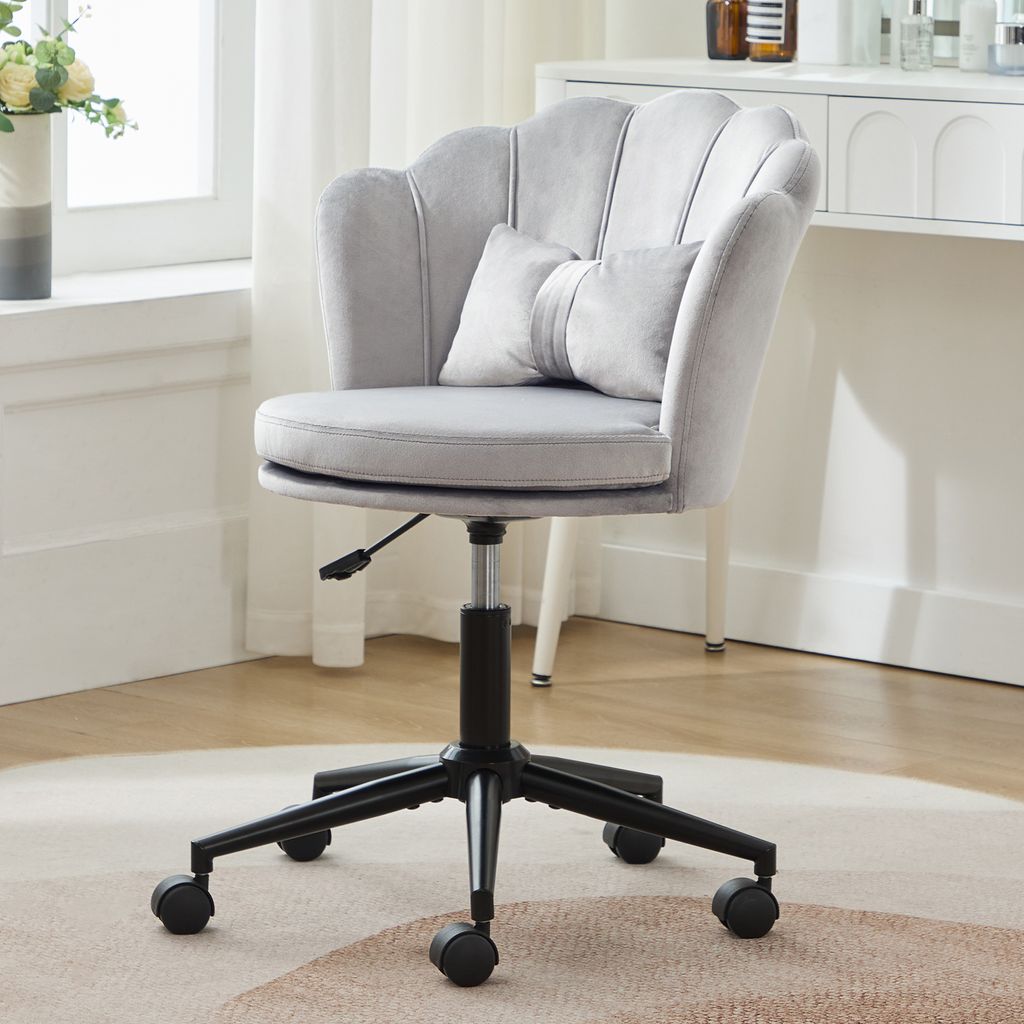 A gray velvet office chair with a scalloped back and a small decorative pillow is shown in a well-lit room.