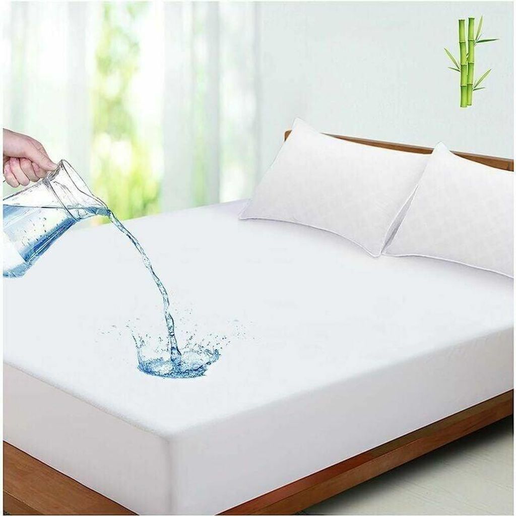 Water being poured onto a white mattress protector on a bed with two pillows.
