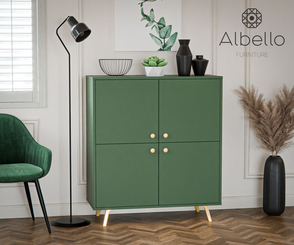 A green cabinet with gold handles is displayed in a room with a green chair, a floor lamp, and decorative items.