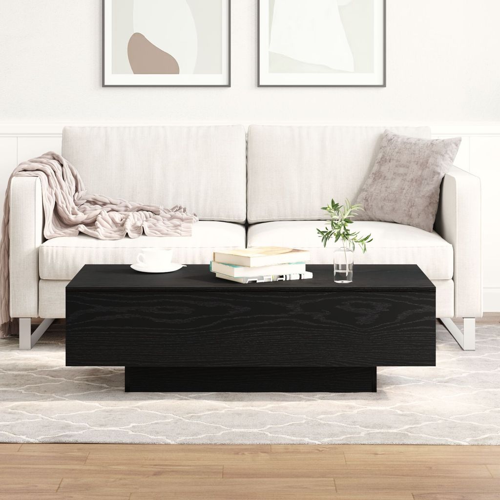 A black coffee table in front of a white sofa in a living room.