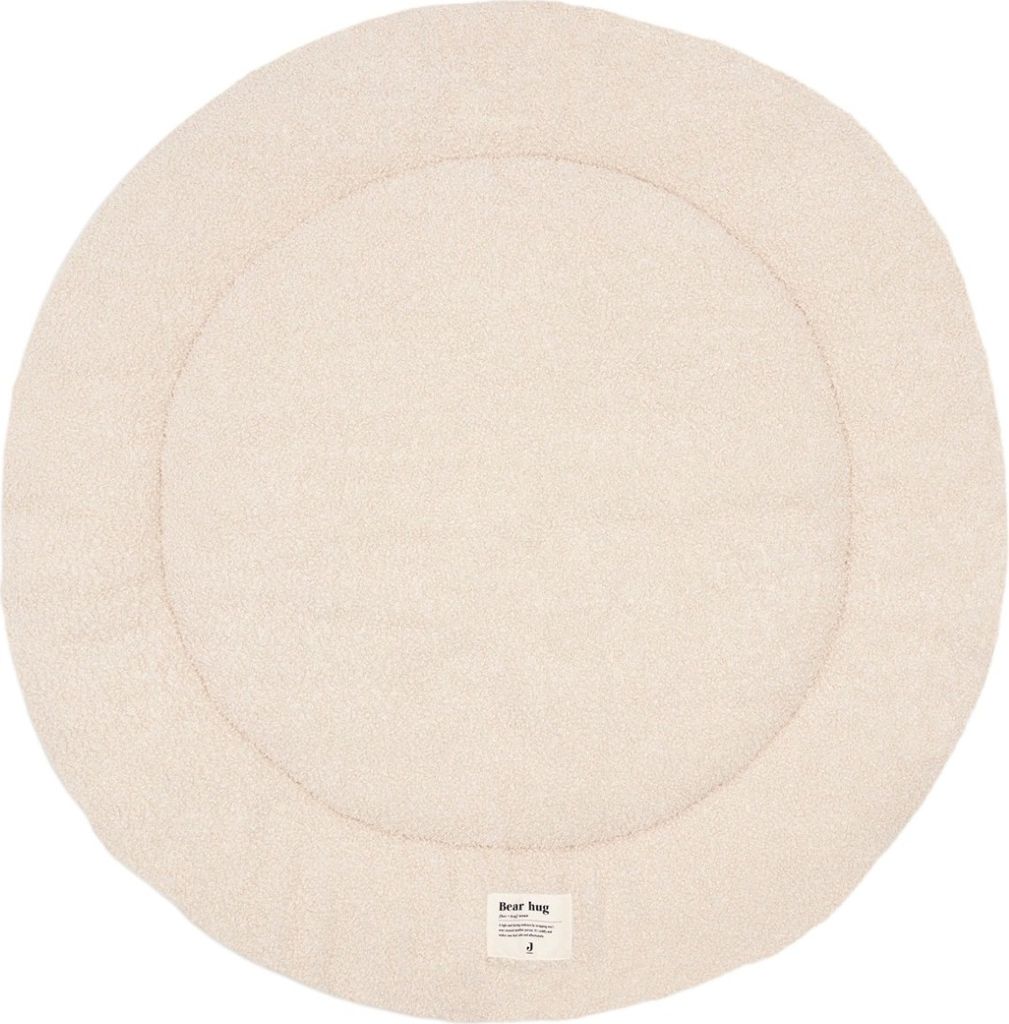 A round, cream-colored mat with a textured surface and a stitched border.