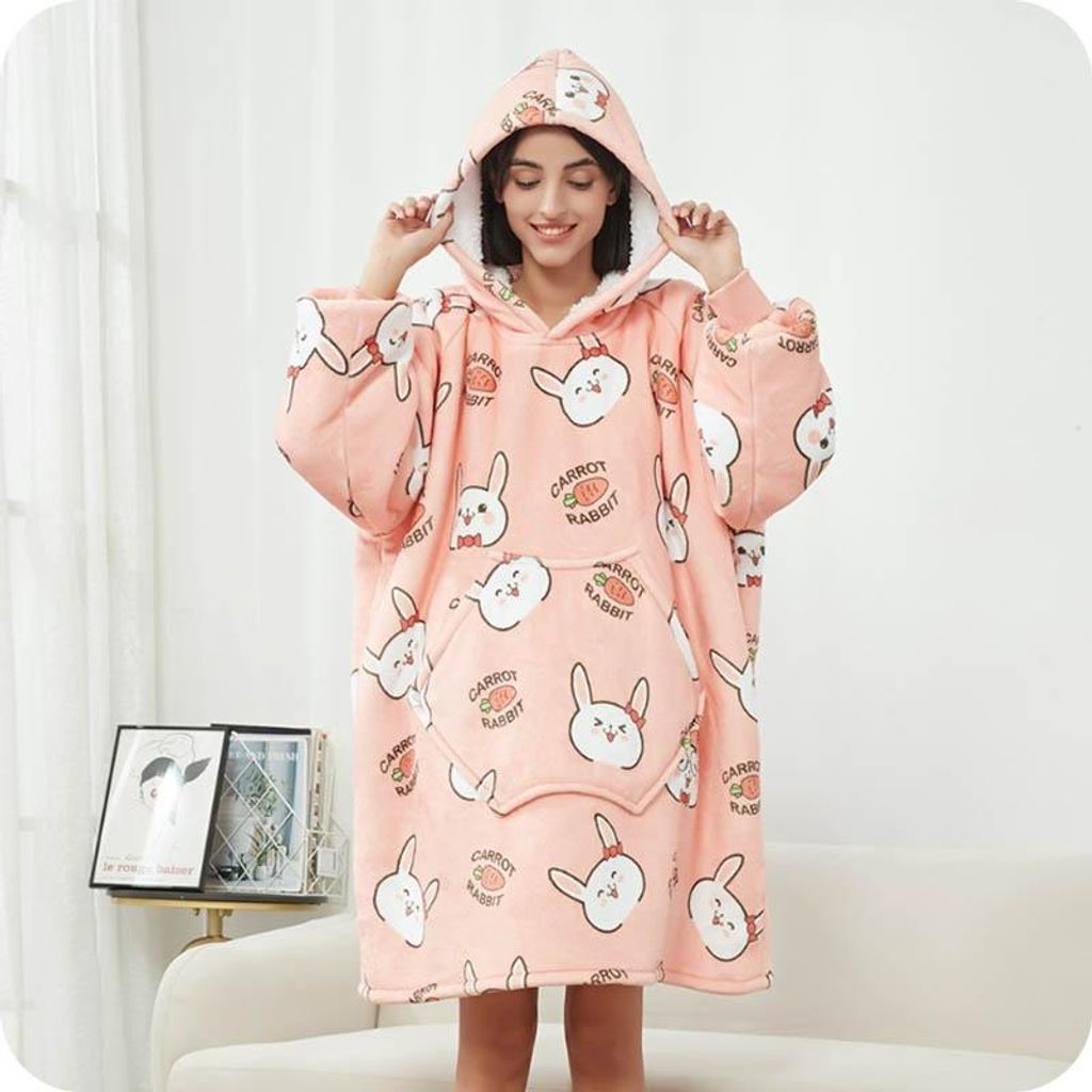 A woman wearing a pink hoodie blanket with a rabbit pattern.