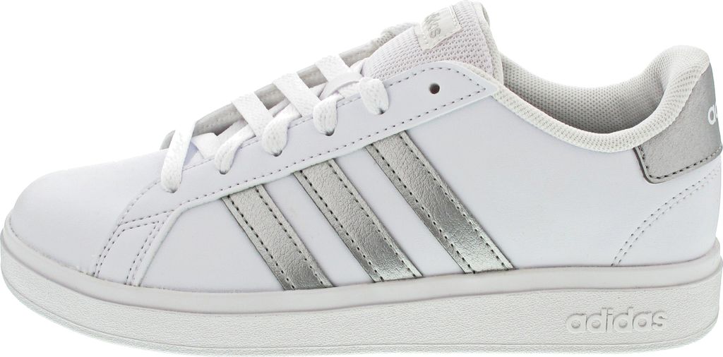 A side view of a white Adidas sneaker with silver stripes.