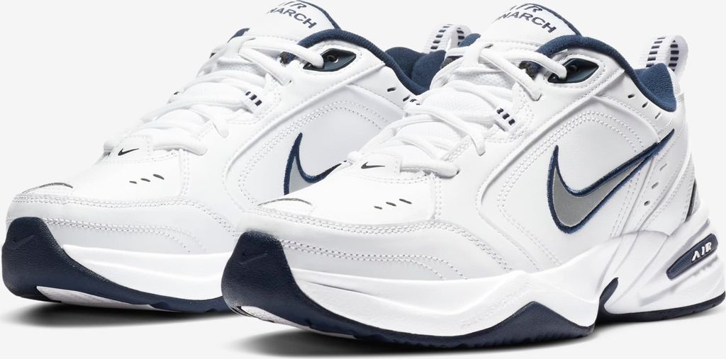 A pair of white Nike Air Monarch IV sneakers with navy blue accents.