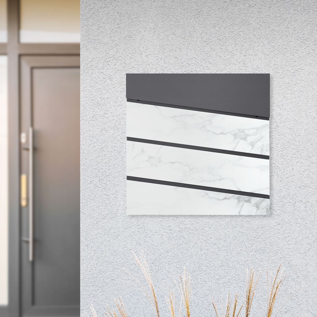 A mailbox with a newspaper compartment mounted on a textured wall next to a door.