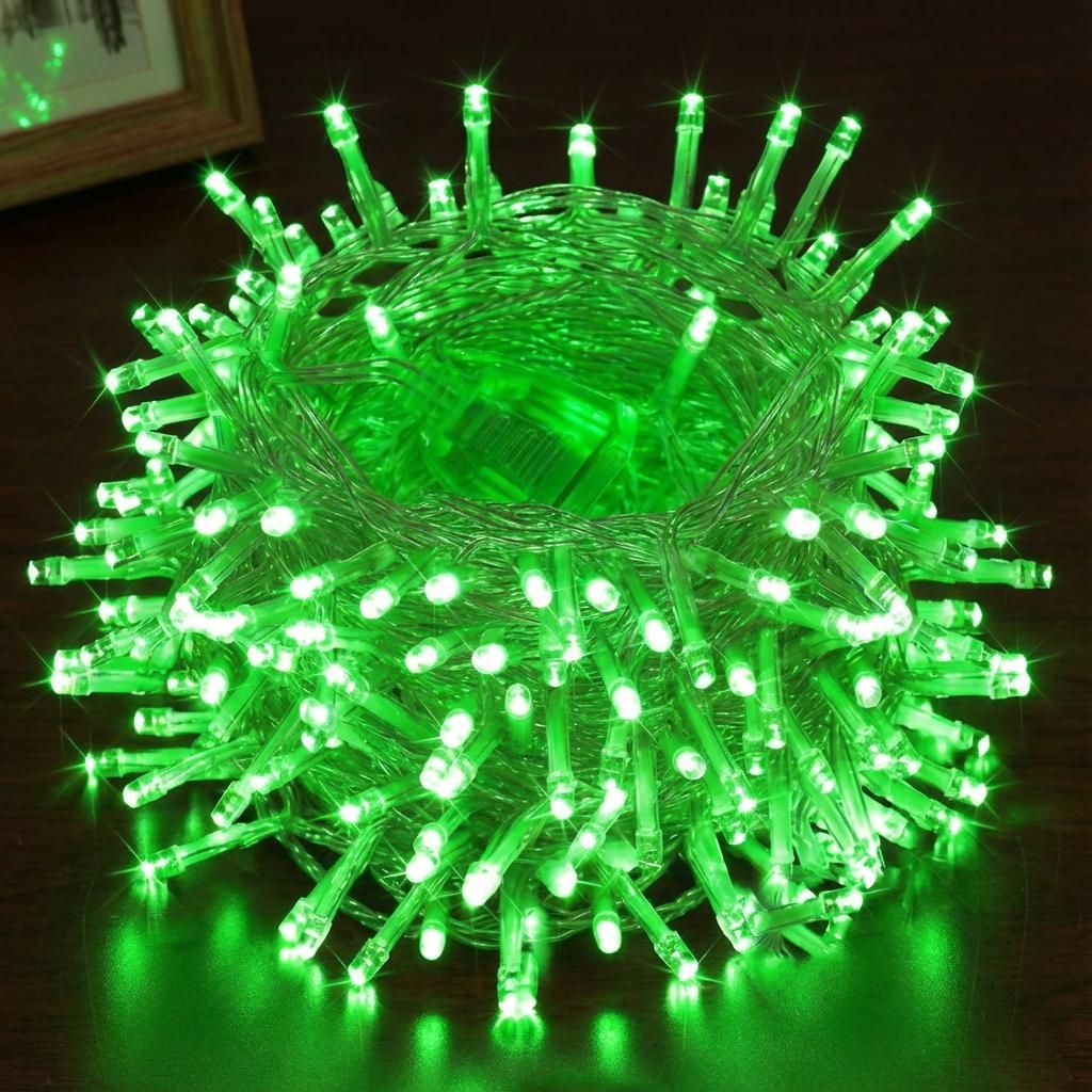 A coiled string of green LED lights on a wooden surface.