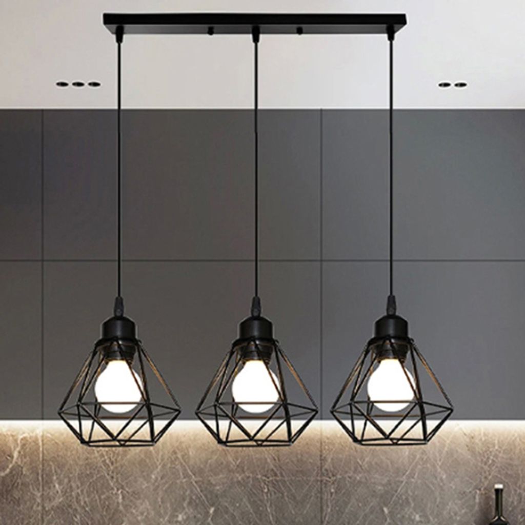 A modern kitchen counter with a three-light pendant fixture hanging above it.