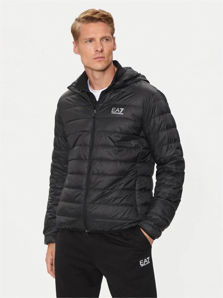 A man wearing a black puffer jacket and black sweatpants.