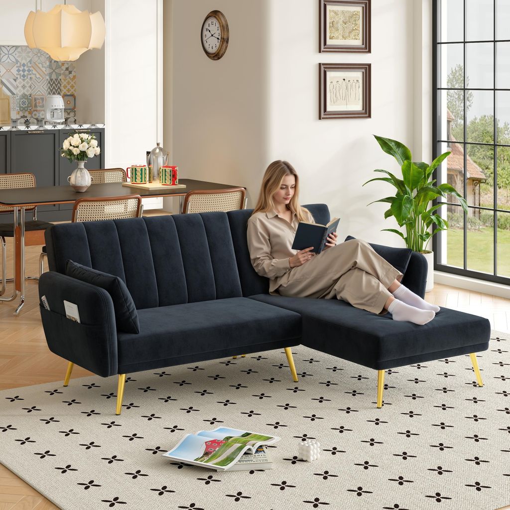 A woman reads a book on a black sectional sofa with gold legs in a living room.