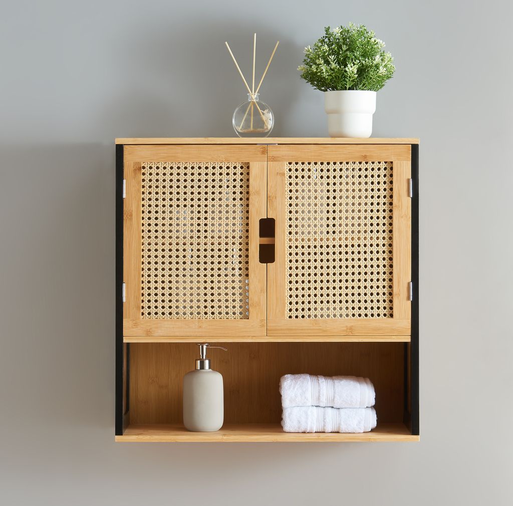 A wall-mounted cabinet with woven doors, a shelf below, and decorative items on top.
