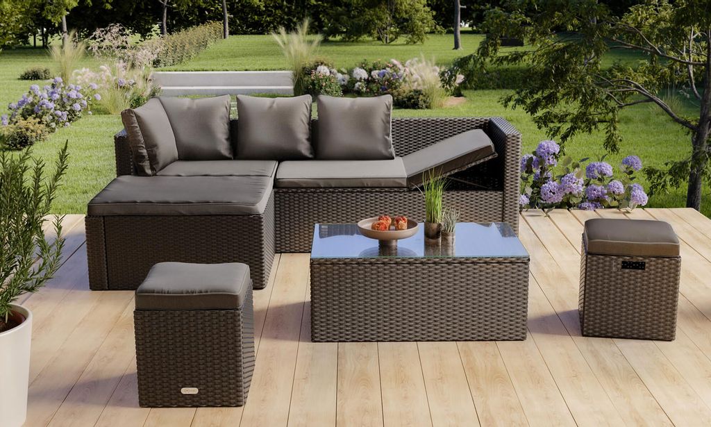 A patio furniture set is arranged on a wooden deck in a garden setting.
