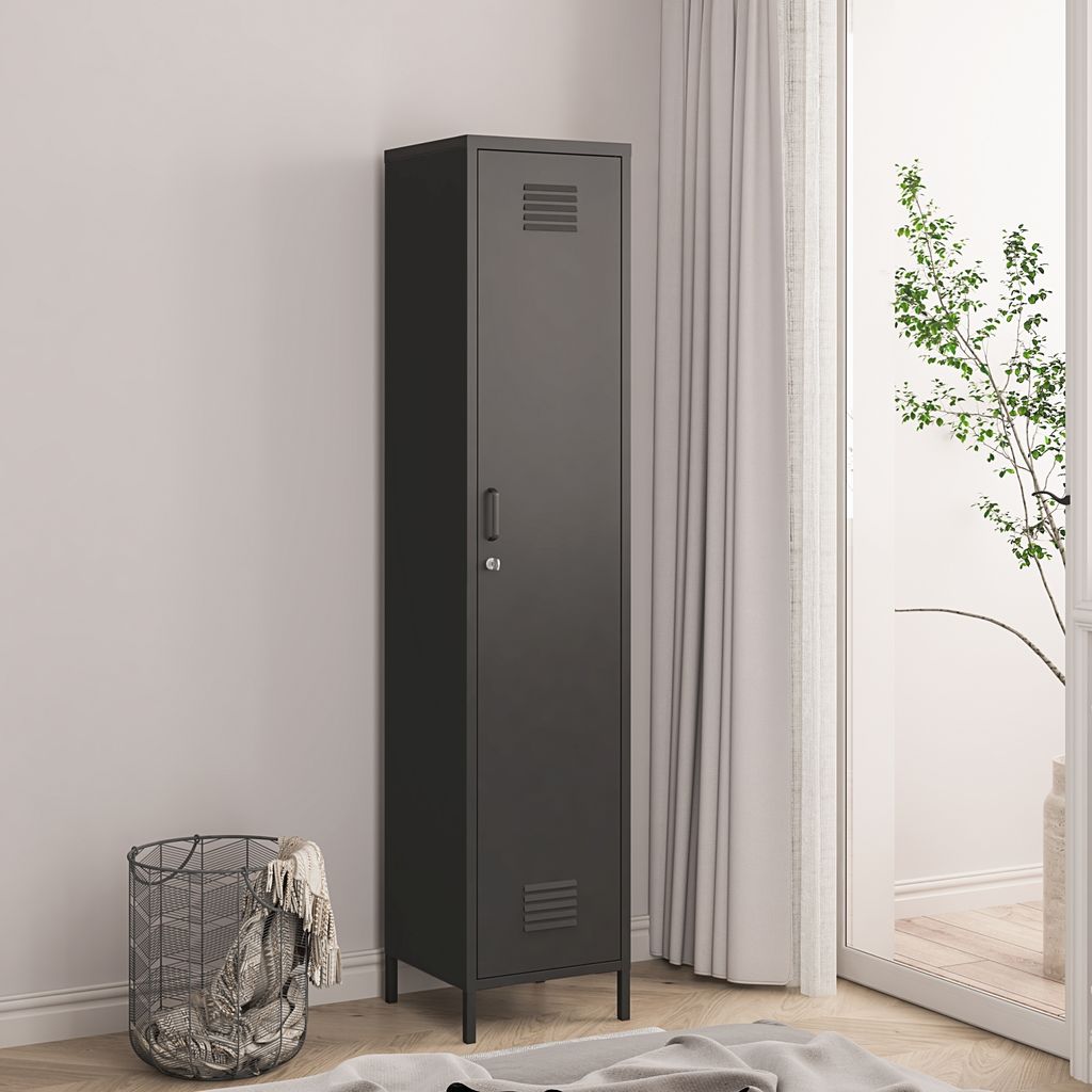A tall, narrow black locker stands against a light gray wall, next to a sheer white curtain. A wire basket with blankets is to the left of the locker.