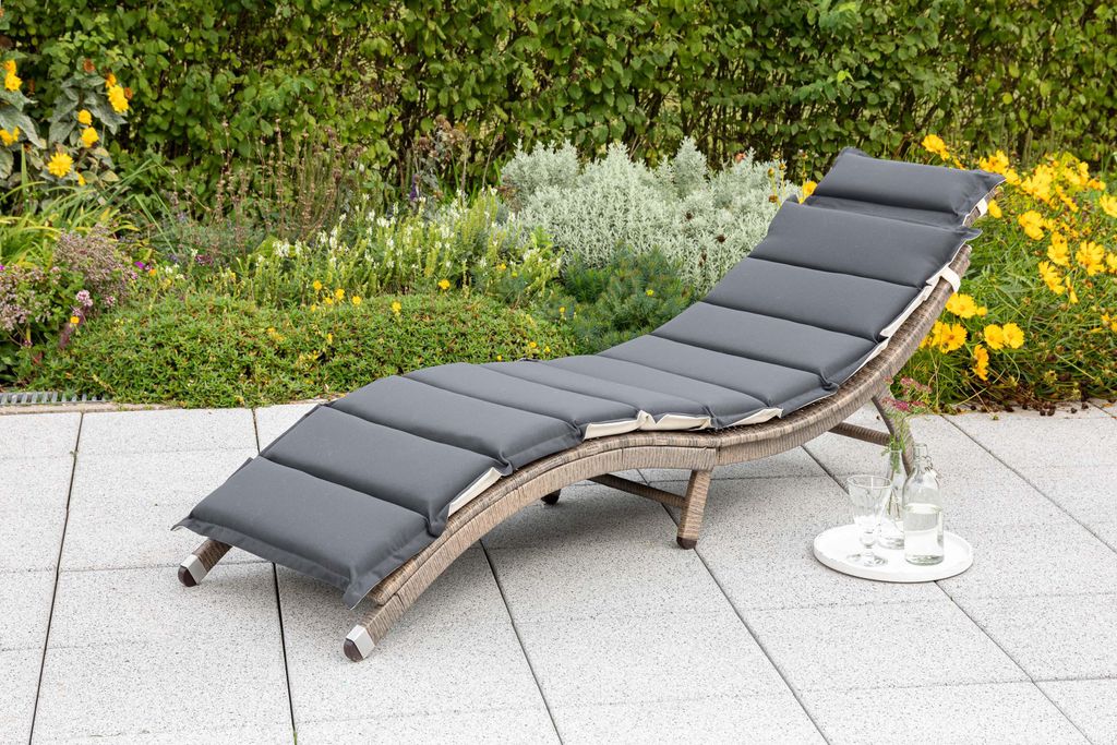 A lounge chair on a patio with plants in the background.