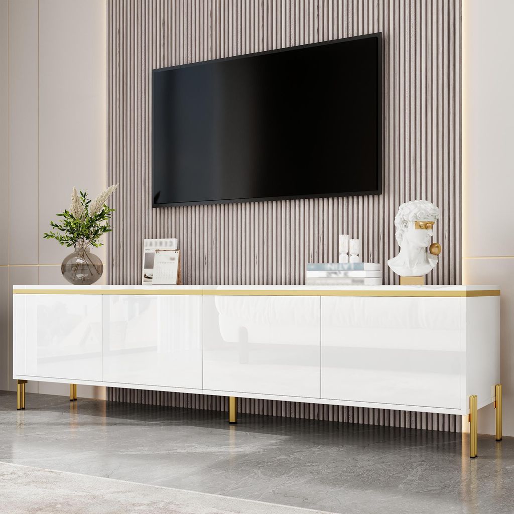 A white TV cabinet with gold accents and metal legs, with a TV mounted on a slatted wall above it.