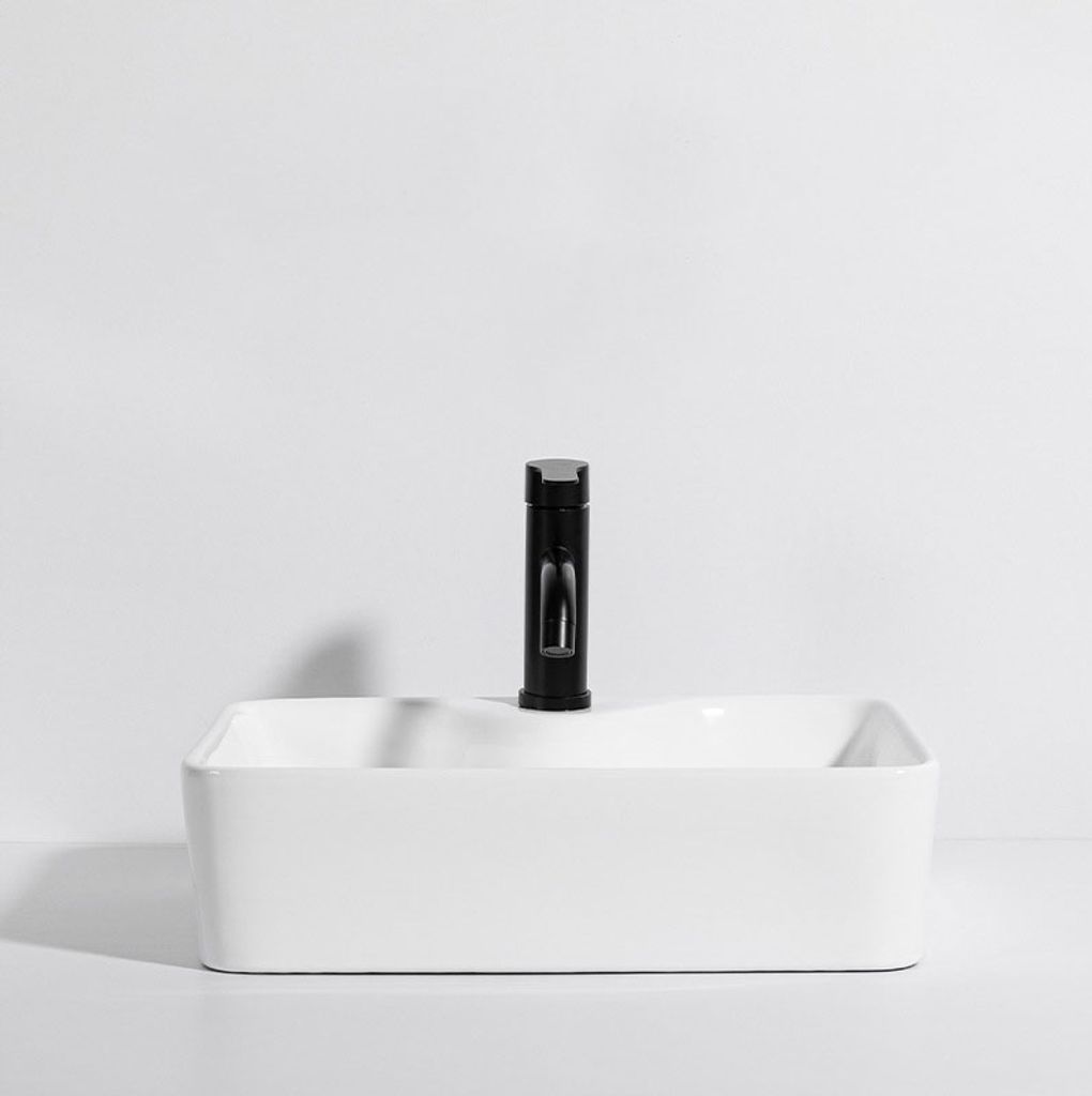 A white ceramic sink with a black faucet against a white background.