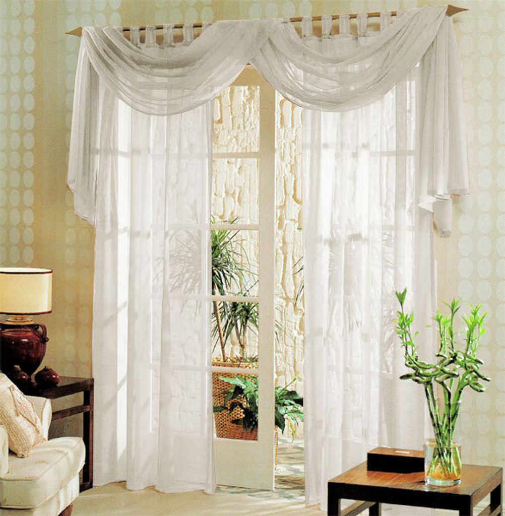 A living room scene with a large window covered by sheer white curtains and a decorative valance.