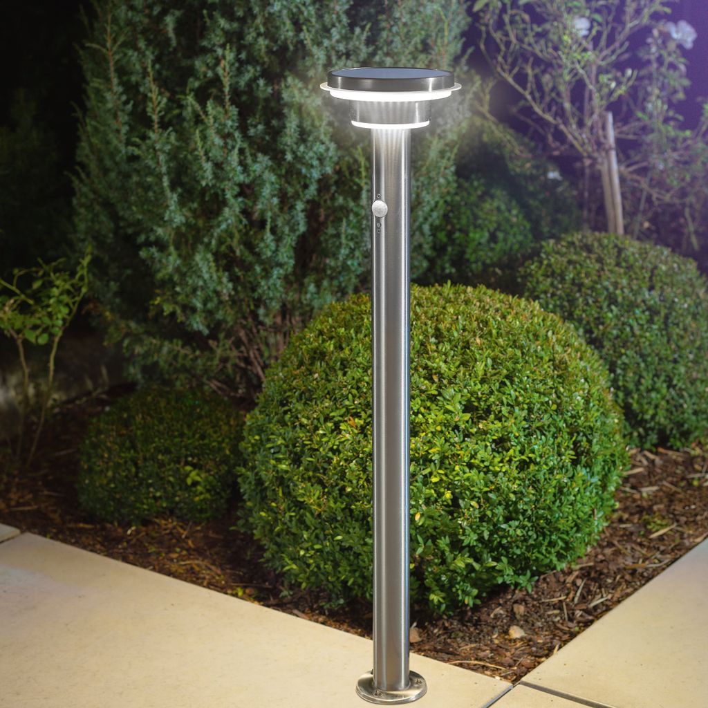 A solar-powered garden light is shown in a garden setting at night.