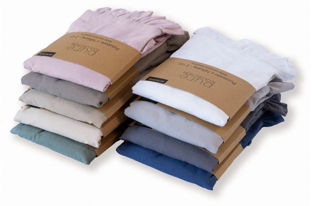 Two stacks of folded pillowcases in various colors, each with a cardboard band around the middle.