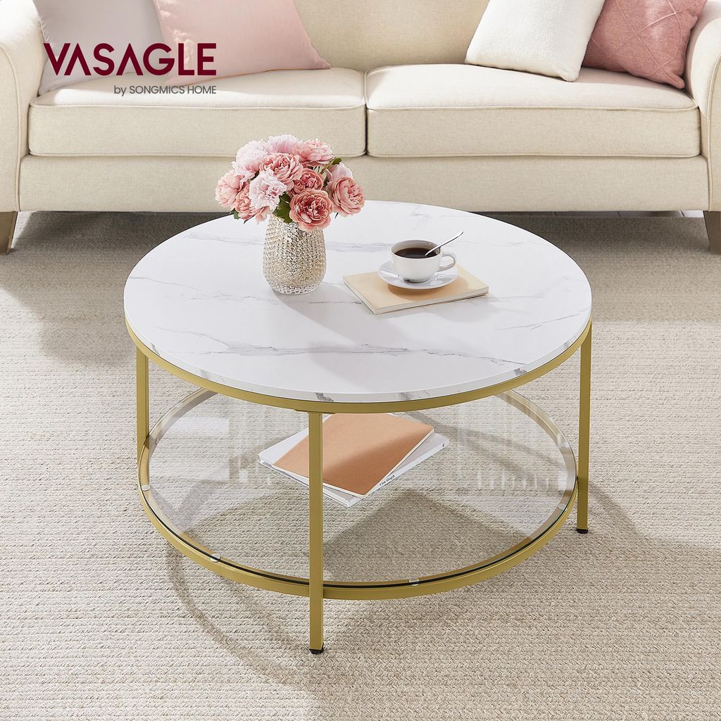 A round coffee table with a marble-like top and gold legs, placed in a living room setting with a sofa and rug.