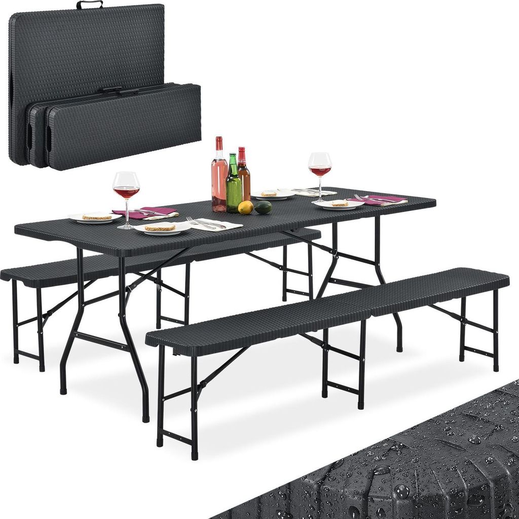 A black folding picnic table and bench set is displayed, set up for a meal with wine bottles and glasses.