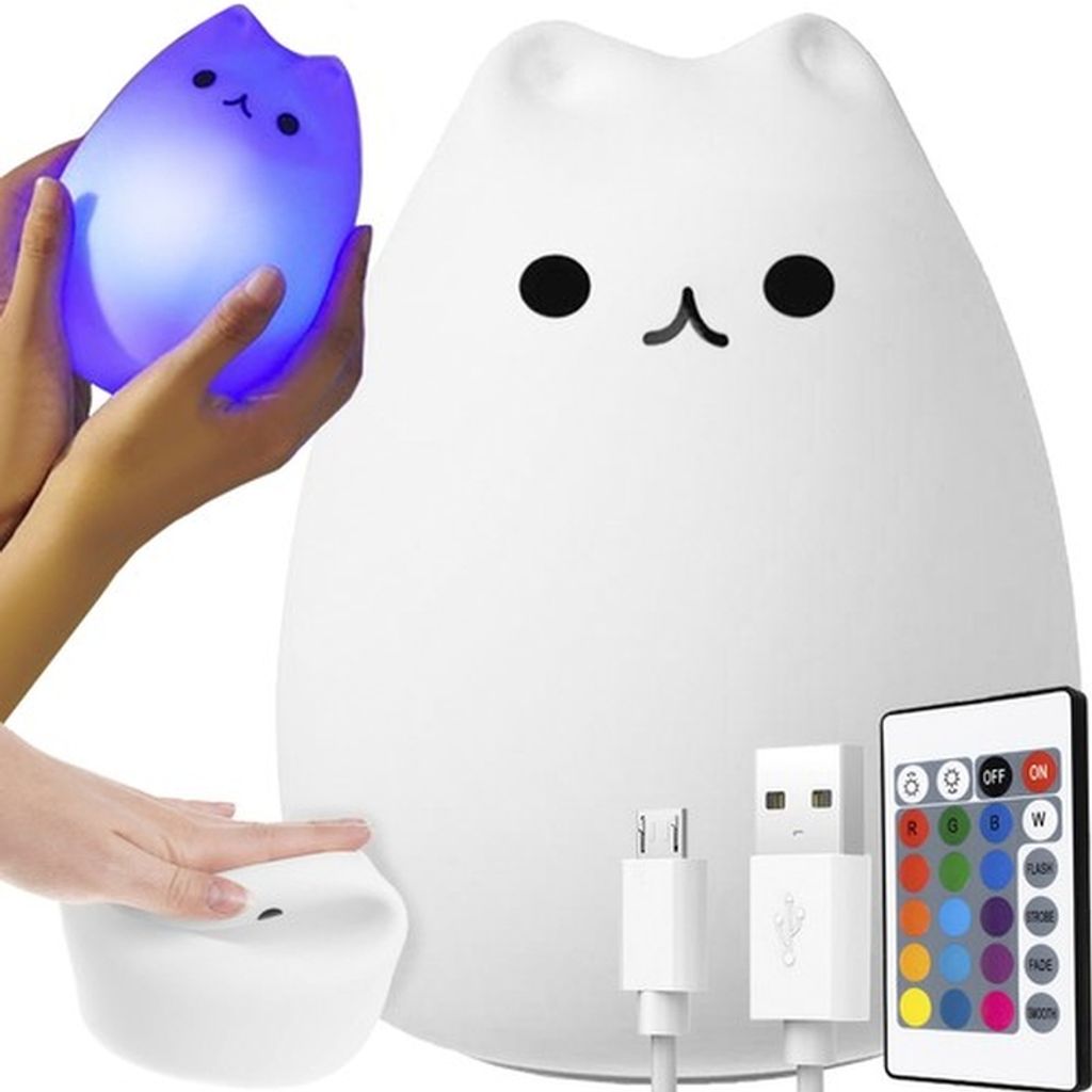 A white cat-shaped LED night light is shown with a hand holding a smaller, illuminated blue version of the same light. A remote control and USB cables are also visible.