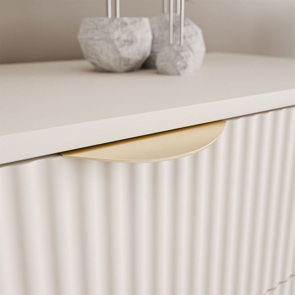 A close-up shot of a drawer handle on a fluted dresser.
