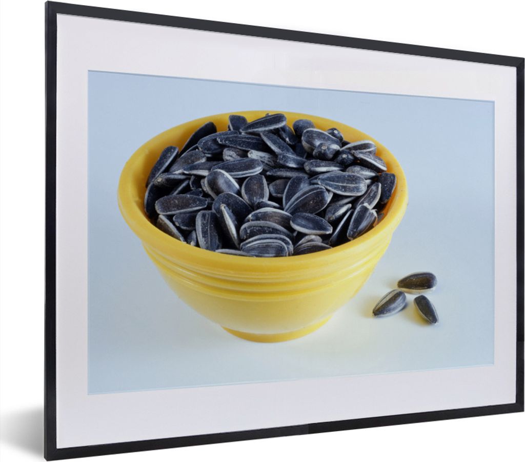 MuchoWow MuchoWow Gerahmtes Poster Sonnenblumenkerne in einer gelben Schale mit ein paar heruntergefallenen Sonnenblumenkernen 40x30 cm - Poste...