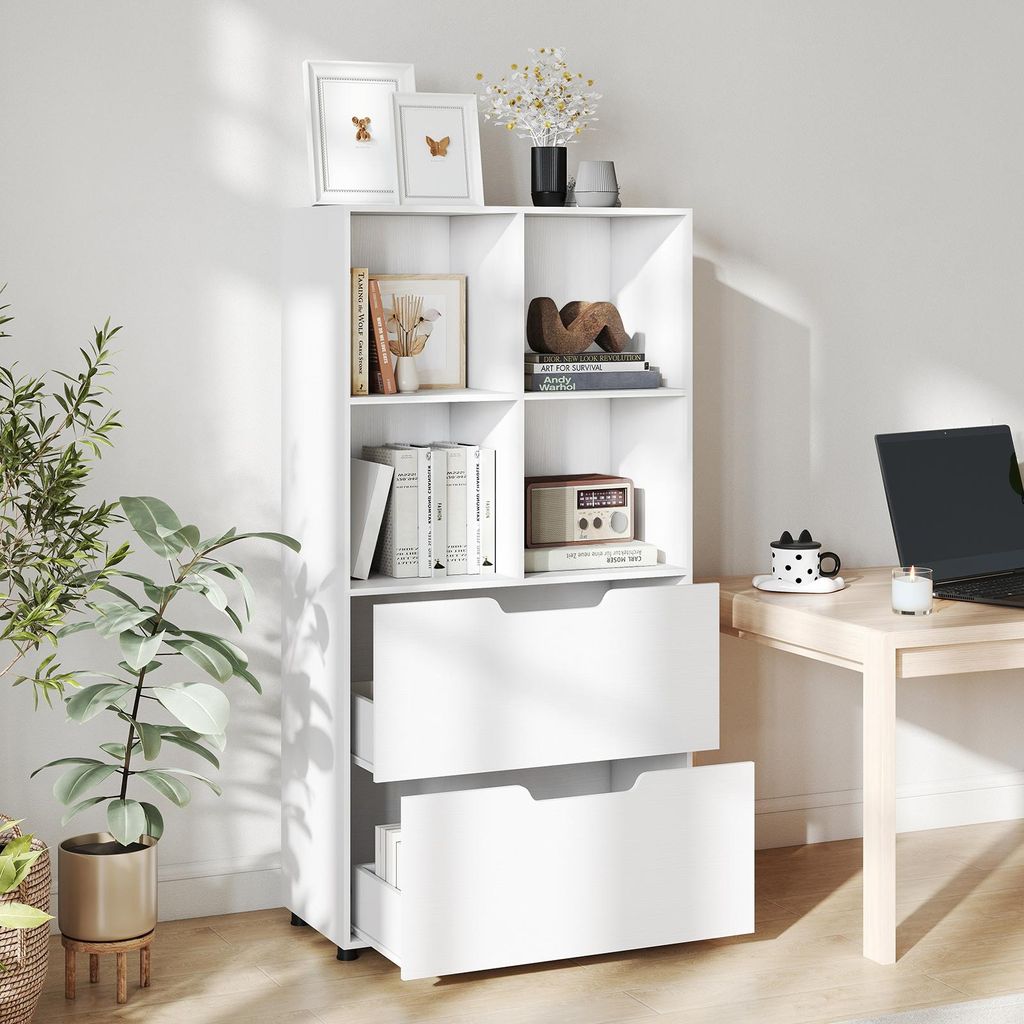 A white bookshelf with two drawers is shown in a room with a plant and a desk with a laptop.
